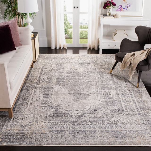 Safavieh Dream Tangier Tapis Traditionnel Surteint Mettant en Vedette un motif Persan Gris Délavé et beige, Tissé Mécaniquement pour la Durabilité, Posé sur des Planchers de Bois Franc Sombres dans un Salon avec un sofa Capitonné Blanc et un Fauteuil Gris Foncé avec un Jeté beige, Près de Portes Françaises Blanches avec des Rideaux Transparents.