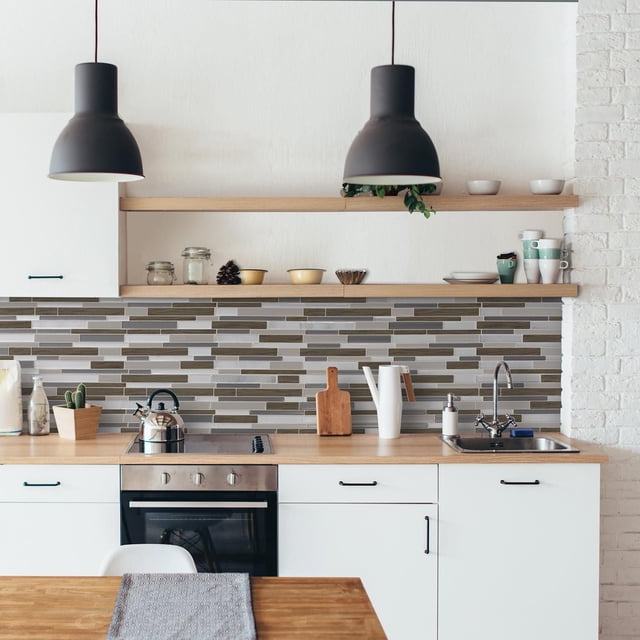 SMART TILES PEEL & STICK BACKSPLASH - MILANO ARGENTO - 4 Pieces 11.55 x 9.63 installed as a grey, brown, and silver rectangular tile backsplash in a kitchen with white cabinets, wooden countertop, stainless steel oven and kettle, sink with chrome faucet, and open wooden shelves with cups and bowls beneath two black pendant lights, suitable for kitchen and bathroom walls.