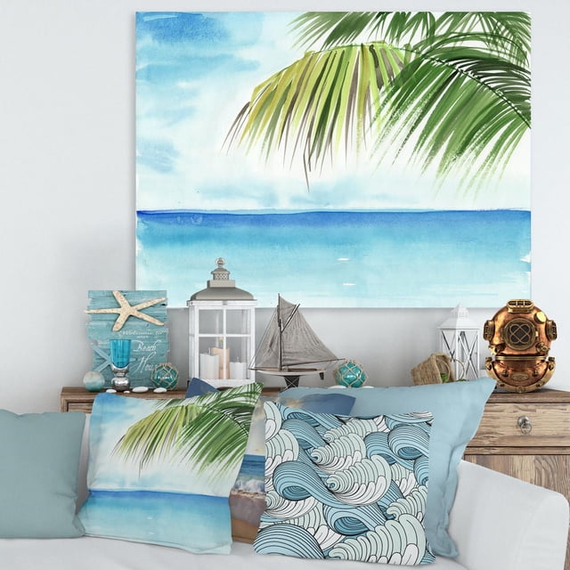 Designart Palm Beach Resort At Dawn III Canvas Wall Art depicting a blue ocean horizon with green palm leaves, gallery-wrapped on premium cotton canvas, displayed above a wooden console with nautical decor and coastal-themed pillows, suitable for enhancing beach-inspired home décor.