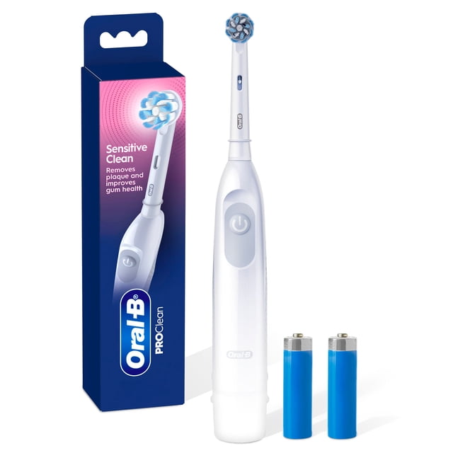 Oral B Pro Clean Battery Toothbrush, Sensitive Clean - White, with one Sensitive round brush head featuring blue and white x-shaped bristles, a white battery-powered handle with a power button, and two AA batteries, displayed next to its blue and pink packaging highlighting plaque removal and gum health benefits.
