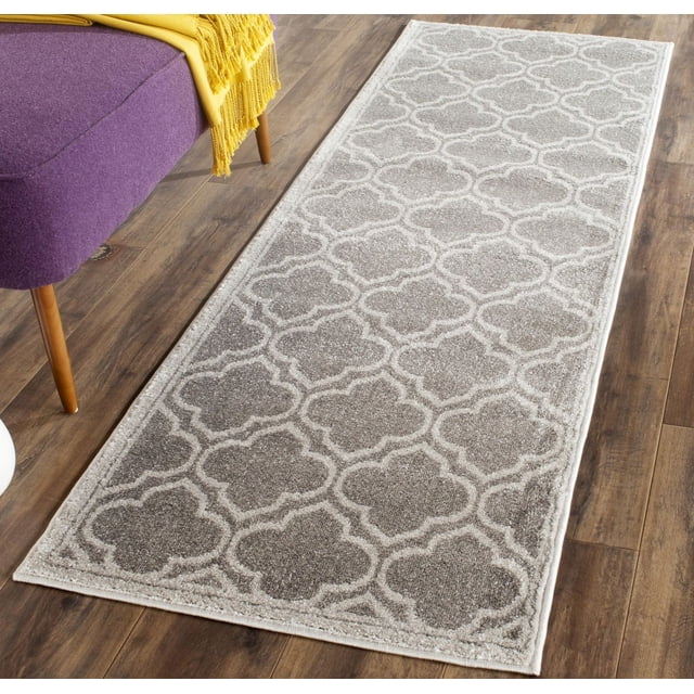 Safavieh Amherst Wilson Tapis Coureur Géométrique Gris et Blanc Cassé avec Motif Treillis Géométrique, Fabriqué en Polypropylène durable Convenant aux Zones Intérieures Ou Extérieures à Fort Achalandage, Posé sur un Plancher de Bois à Côté d'Un Banc Violet avec un Jeté Jaune.