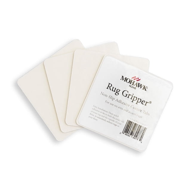 Mohawk Home Rug Corner Gripper Rug Pad 4 Piece Set in white, showing four square non-slip adhesive corner tabs with one tab displaying the product label, designed to keep indoor area and accent rugs secure on hard floors without added bulk.