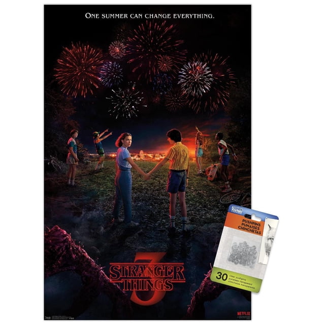 Netflix Stranger Things: Season 3 - Key Art Wall Poster, 22.375" x 34" framed, depicts six children standing on a grassy hill at night watching vibrant fireworks over a small town. Two children hold hands in the center with the Stranger Things 3 logo below, framed by dark shadowy figures. Ideal for home décor or themed party decoration.