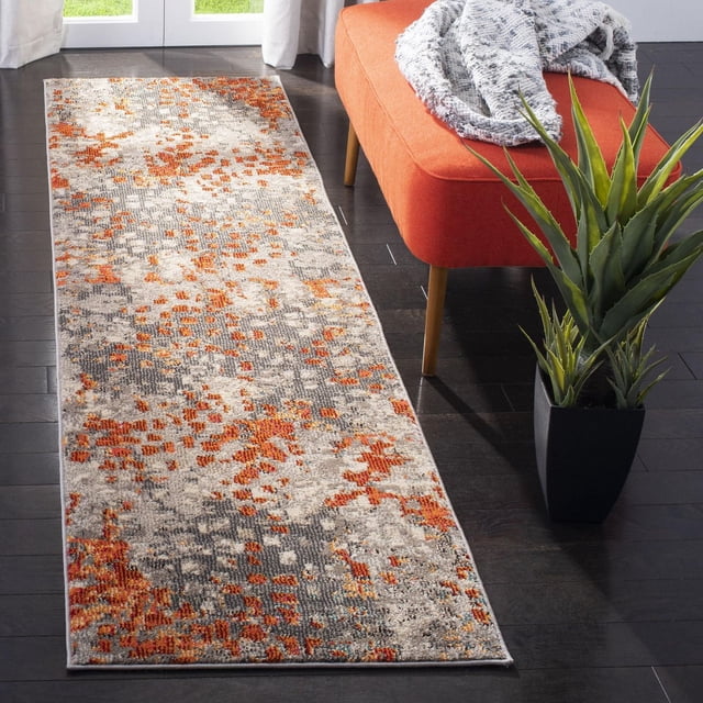 Safavieh Monaco Driskoll Abstract Area Rug runner made of durable power-loomed polypropylene with an abstract orange, grey, and beige pattern, displayed on dark hardwood flooring next to an orange bench and a potted green plant, ideal for adding Bohemian-chic style to accent spaces.