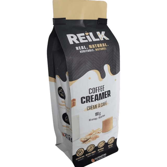 Reilk Crème à Café Naturelle, un Sac Refermable de 180 g Conçu avec du Vrai Lait-Crème et de l'Avoine Biologique pour un Style de Vie Naturel. l'Emballage Met en Valeur des Caractéristiques Sans Gluten, Réduites en Lactose et Sans Additifs, avec des Visuels d'Une Tasse de Café et d'Avoine. Parfait comme Crème Non Laitière pour un Goût Riche et une texture Lisse.