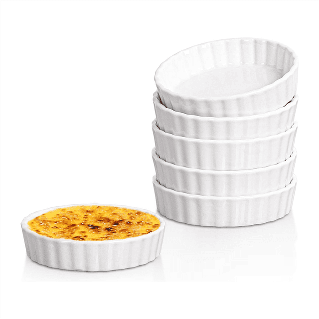 5 Oz Creme Brulee Ramekins, a set of six round fluted quiche dishes made of white ceramic, displayed in a stack with one filled with creme brulee in the foreground. These oven-safe ramekins are ideal for baking, souffles, desserts, and more, with a simple and classic design.