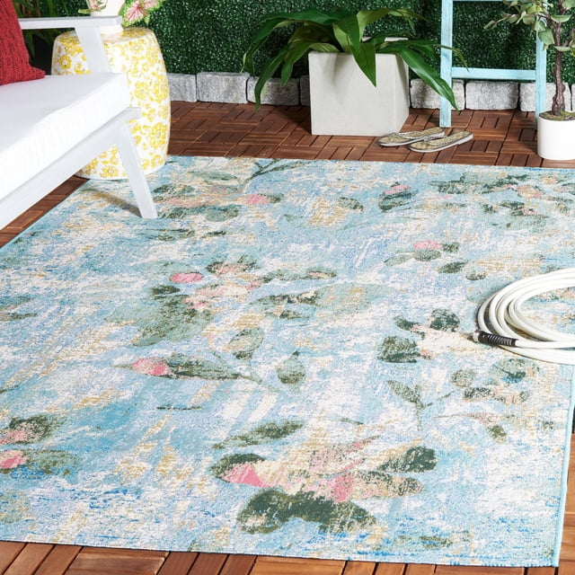 SAFAVIEH Barbados Cedric Tapis d'Intérieur/extérieur à Motif Floral avec base Bleue et Motifs Floraux Abstraits Vert, Rose et beige, Posé sur un Plancher de patio en Bois avec Mobilier d'Extérieur Blanc, Tabouret en Céramique Jaune, Plantes en Pot et Tuyau de Jardin Blanc Enroulé, Convient pour Rehausser les Espaces de Vie Extérieurs.