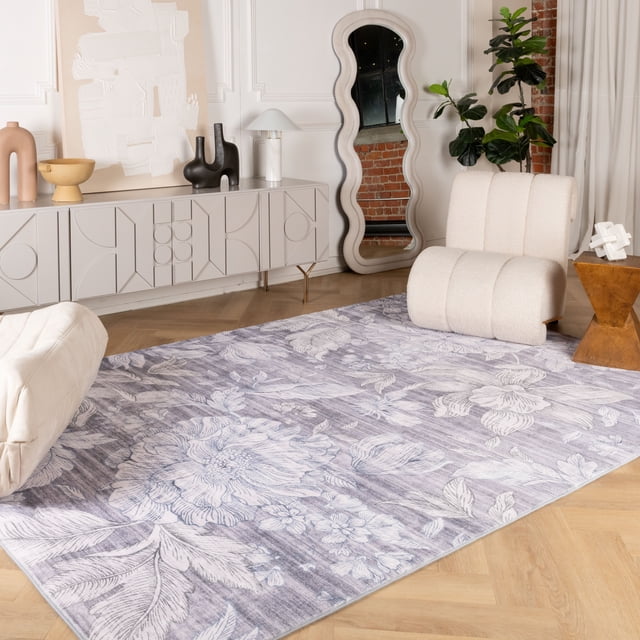 Modern floral indoor area rug featuring large white flowers and leaves on a muted purple background, placed in a contemporary living room with beige furniture and decorative accents.