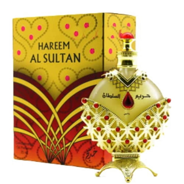 Hareem Al Sultan Gold - Concentrated Perfume Oil by Khadlaj (35ml). A luxurious perfume bottle with intricate gold and red detailing, featuring a teardrop-shaped red gem at the center. The background includes the matching decorative packaging in gold and red with ornate patterns.
