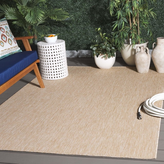SAFAVIEH Beach House Jacinth Tapis d'Intérieur/extérieur Uni en Fil Synthétique Tissé beige, Exposé sur des Carreaux Extérieurs Gris avec une Chaise en Bois avec Coussin Bleu, table d'Appoint Tissée Blanche, Plantes en Pot et vases en Céramique, Conçu pour une Utilisation durable dans les Espaces de Loisirs Intérieurs Ou Extérieurs à Fort Achalandage.