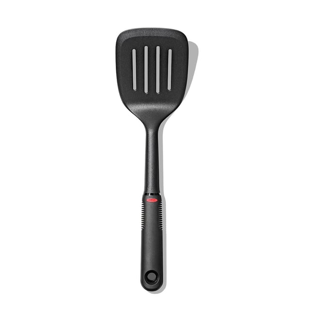 OXO SW Nylon Square Turner with a broad black nylon slotted head, sturdy neck, and soft black handle featuring a red OXO logo and hanging hole, heat resistant to 450°F and safe for non-stick cookware, also suitable for flipping delicate foods like eggs and grilled cheese.