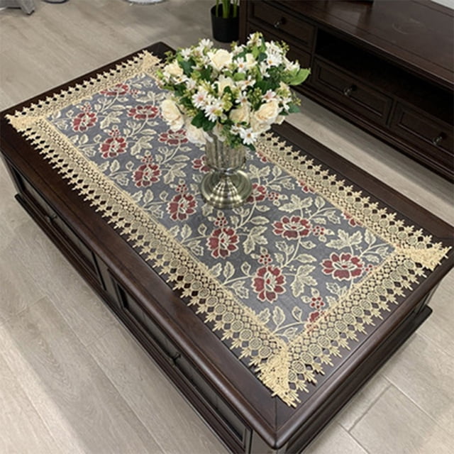 Luckyn European Embroidered Tablecloth Western Tea Table Runner Coffee Table Flag Rectangle Lace Dust Cover, measuring 50x100cm. The tablecloth features a hollow carved design with intricate crochet handmade lace edges and a floral embroidered pattern in red and beige tones on a grey background. It is displayed on a dark wooden coffee table with a vase of white and yellow flowers as a centerpiece.