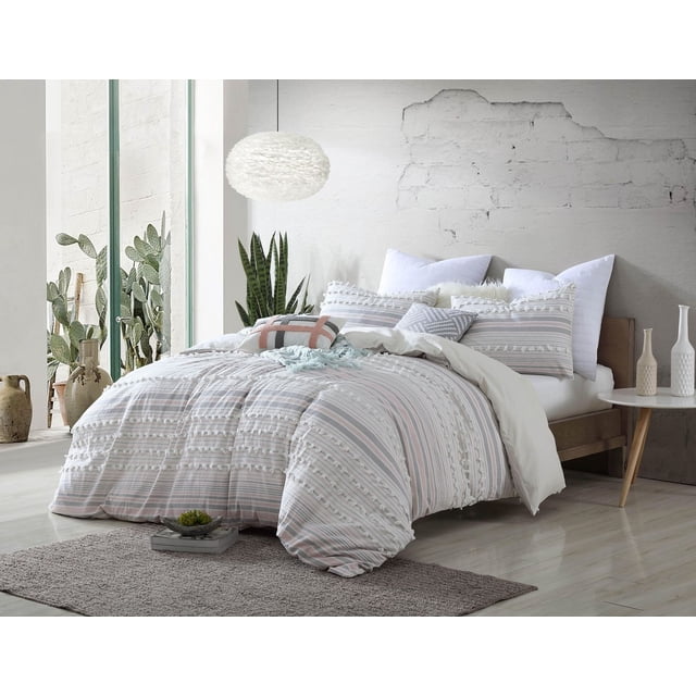 Ensemble de Douillette 5 Pcs en Coton sur un Cadre de Lit en Bois avec une Douillette Rayée et des Couvre-Oreillers Assortis Présentant des Détails Texturés Tuftés dans des Tons Neutres Doux. Fait de 100 % Coton, Lavable à la machine et Certifié Oeko-Tex. la Chambre Comprend un Tapis Gris, des Plantes en Pot Près d'Une Grande Fenêtre, et une table d'Appoint Ronde avec des vases en Céramique.
