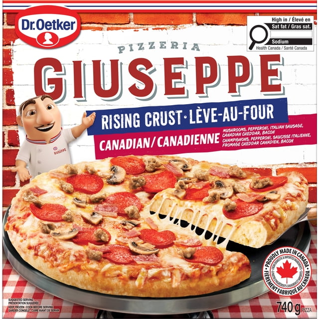 Dr. Oetker Giuseppe Pizzeria Rising Crust Canadian Pizza showing a cooked rising crust pizza topped with mozzarella, pepperoni, Italian sausage, mushrooms, bacon, and Canadian cheddar cheese, with a slice lifted by a pizza server on a black tray, set against a red brick wall and checkered tablecloth.