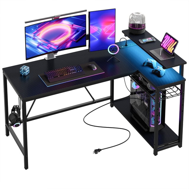 Bestier 52" Gaming Desk with LED Lights, an L-shaped desk in carbon fiber finish featuring a spacious 52.2"L x 31.5"W desktop. Equipped with 7-color RGB LED lights and 22 dynamic modes for a personalized gaming experience. Includes a 6"H removable monitor stand, 3 AC outlets, and 2 USB ports for convenient device charging. Features adjustable shelves for storage and a reversible design to fit any corner. Sturdy metal frame with adjustable leg pads ensures stability on uneven floors.