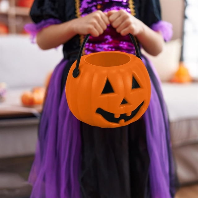 TopLLC Halloween Pumpkin Bucket, a small plastic pumpkin-shaped candy bucket with a black handle, held by a child dressed in a purple and black Halloween costume. The bucket features a classic jack-o'-lantern face and is ideal for carrying candy during Halloween parties or trick-or-treating. Made of durable PVC material, it is lightweight and reusable.
