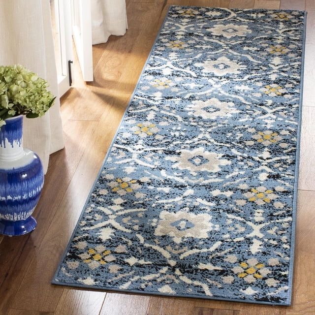 SAFAVIEH Amsterdam Karenza Geometric Floral Area Rug runner with a blue base and cream and yellow geometric floral patterns, power loomed from durable synthetic yarns, placed on a hardwood floor beside a blue and white ceramic vase with green hydrangeas, suitable for rustic-chic hallway décor.