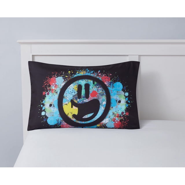Mainstays Kids Taie d'Oreiller Imprimée 20 par 30 Pouces en Microfibre 100 % polyester avec Fond Noir et Motif de Peinture Éclaboussée Colorée Mettant en Vedette un Grand Visage Souriant Noir avec une Bouche Ouverte, Exposée sur un Lit Blanc avec une Tête de Lit Blanche, Idéale pour Égayer la Literie des Enfants.