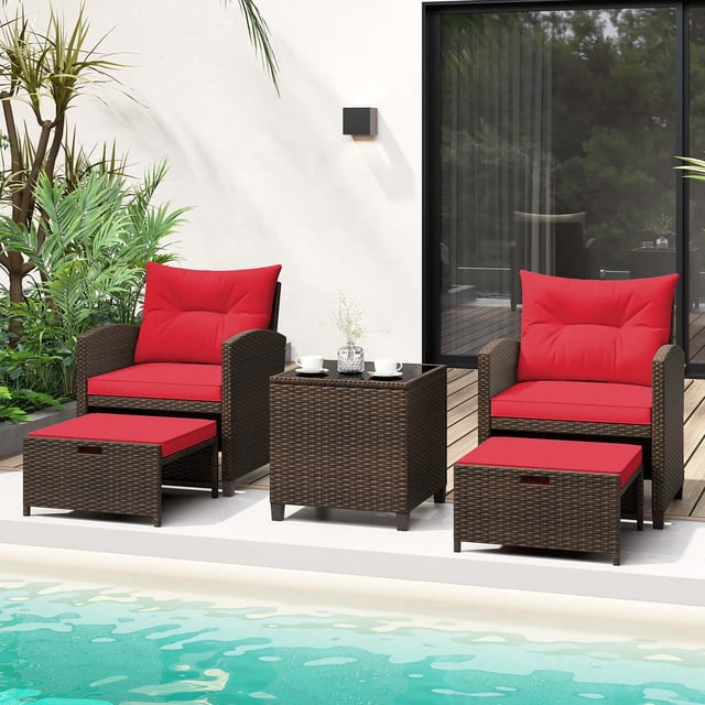 Costway 5 PCS Patio Rattan Furniture set with two mix brown wicker chairs featuring ergonomic backrests and curved armrests, two ottomans with red cushions, and a tempered glass coffee table. Ideal as an outdoor patio conversation set, displayed poolside with greenery and a modern patio backdrop.