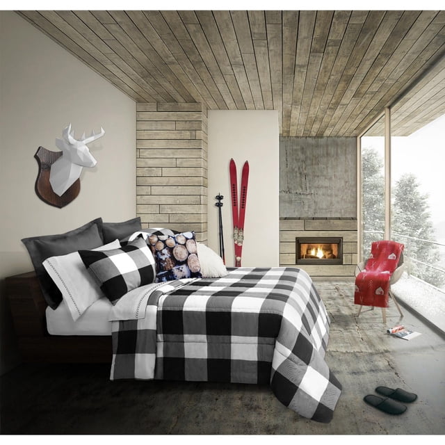 Safdie & Co. Ensemble de Douillette 3 Mcx K Revers. Carreaux Buffalo Blanc/noir sur un Lit Très Grand dans une Pièce Rustique Moderne avec Plafond et Murs à Panneaux de Bois, Comprenant une Douillette à Carreaux Buffalo Noire et Blanche et des Couvre-Oreillers, des Oreillers Décoratifs Incluant une Impression de Bûches, une Tête de Cerf Géométrique Blanche à Monter au Mur, des skis Rouges avec des Poteaux, un Foyer en Béton, une Chaise à Motif Rouge Près d'Une Grande Fenêtre avec des Arbres Enneigés à l'Extérieur, et des Pantoufles Sombres au Sol. Cet Ensemble de Literie