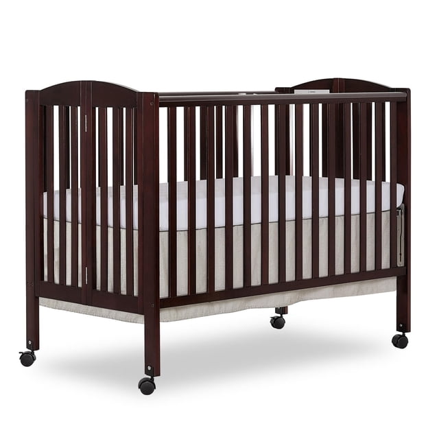 Dream On Me Folding Full-Size Crib in dark wood finish with vertical slats and stationary rail design, featuring dual safety hooded locking wheels and a white mattress, shown in a front 3/4 view on a white background, ideal nursery furniture for growing families.
