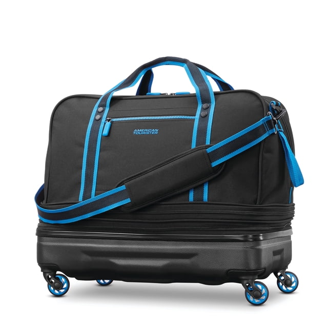 American Tourister Expandable Hybrid Duffle in black with blue trim, featuring a soft 600D polyester upper section and a rugged molded hardside bottom with four blue-accented spinner wheels, dual handles, removable padded shoulder strap, and expandable compartments offering 120% extra packing capacity, ideal for gym and travel use.