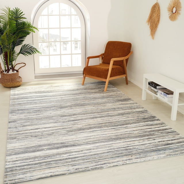 Blue grey abstract striped Rug Branch Atlas Lines indoor area rug displayed in a modern living space with natural light, featuring a brown armchair and minimalist decor.