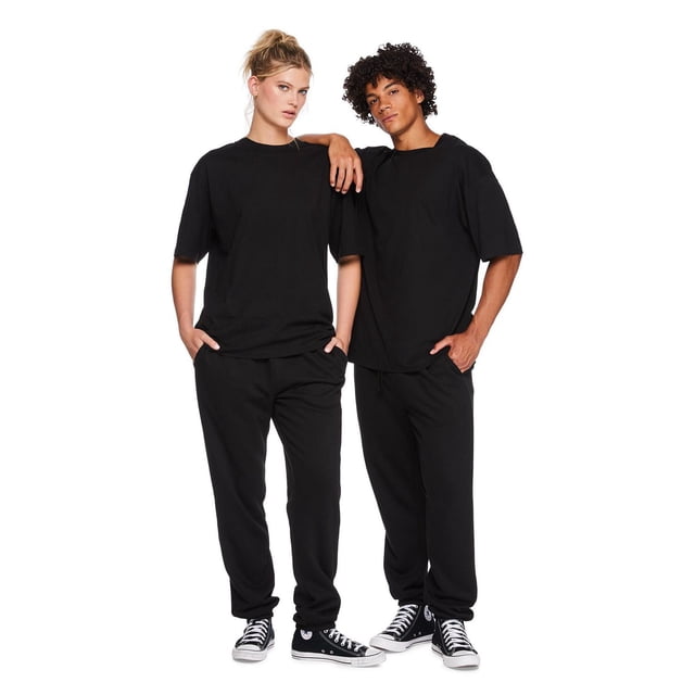 Two models wearing No Boundaries all gender oversized black cotton short sleeve tees paired with casual black pants and sneakers.