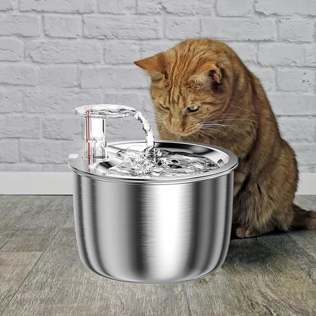 Cat Water Fountain 2L with Filter Water Feeder made of 304 stainless steel, designed for pet hydration with a silent water pump and circulating ten-layer filtration system. The fountain includes a buoy water level monitor and adjustable water flow settings. A ginger cat is positioned near the fountain, which is placed on a wooden floor against a white brick wall.