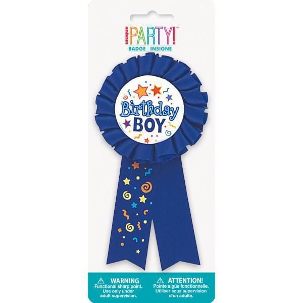Birthday Boy Award Badge with blue fabric rosette and two ribbon tails decorated with colorful stars and confetti, featuring 'Birthday Boy' text in playful font on white circular center, attached to white backing card with safety pin and warning label, perfect for birthday party celebrations.