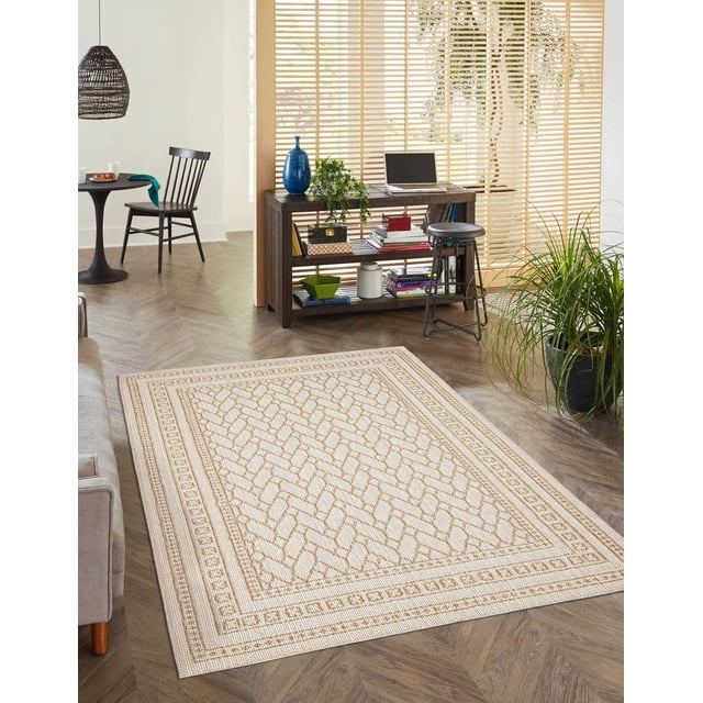 ECARPET Jute Style Area Rug for Bedroom, Living Room, Dining Room Francesca Collection in a modern room with herringbone hardwood floors. The 8 by 10-foot ivory rug features tan geometric patterns and a bordered design with a jute style texture. Positioned near a wooden console table with books, a blue vase, and a laptop, alongside a black metal stool. The space includes a black round dining table with a chair, a woven hanging lamp, and wooden blinds filtering natural light. Suitable for high-traffic indoor areas, this fade- and shed-resistant rug complements coastal and country-inspired interiors and is often used in home offices or foyers.