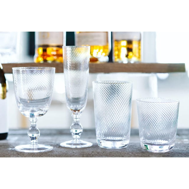 Retro Glasses Set of 4 with two lead-free crystal stemmed glasses and two textured tumblers featuring diagonal patterns, displayed on a wooden surface with blurred bottles in the background, ideal for wine, champagne, juice, or cocktails in home or restaurant settings.