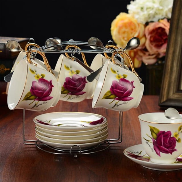 Oleegame 1PC Hold 6 Coffee Cups And 6 Tea Cup And Saucer Display Rack Modern With Hook Cup Holder For Ornament in silver. The stainless steel rack features a polished finish and upward arc hooks to securely hold six cups and saucers. The base is 7.3 inches in diameter for stability, and the design is suitable for organizing mugs, coffee cups, and tea cups. Displayed on a wooden table with floral-patterned cups and saucers, the rack is ideal for kitchens, living rooms, or coffee bars.