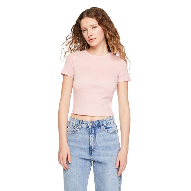 No Boundaries Women's Rib Baby Tee in light pink, shown front-facing on a model wearing light blue high-waisted jeans. The rib knit tee features a crew neckline, short sleeves, and a cropped fit suitable for casual wardrobe layering and versatile styling.