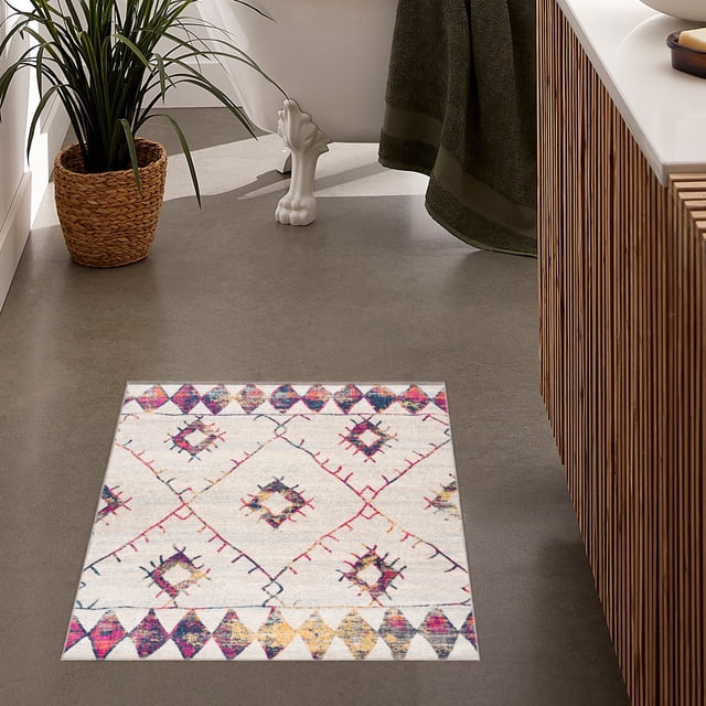 SAVANNAH CREAM2X3 cream 2x3 area rug with abstract diamond and geometric patterns in pink, blue, and yellow, made of 100% polypropylene with jute backing, displayed on a grey floor in a bathroom setting with a wicker plant pot, clawfoot tub, and wooden vanity.