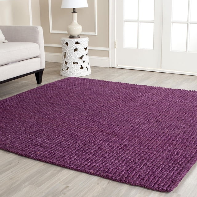Safavieh Natural Fiber Levi Braided Area Rug in other color, displayed in a living room with light wood flooring, beige sofa, and white ceramic side table with lamp, featuring a textured braided weave made from natural fibers suitable for coastal or casual interiors.