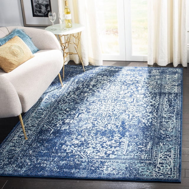 Safavieh Evoke Trena Tapis Traditionnel pour Aire avec un Motif vintage Bleu et Blanc Usé et une Douce Frise en Polypropylène, Posé sur un Plancher de Bois Franc Foncé dans une Pièce Lumineuse avec des Rideaux Transparents, à Côté d'Un sofa beige avec des Coussins Or et Bleu et une table d'Appoint Ronde Blanche Tenant une Bouteille de Vin et un Verre, Idéal pour Ajouter un style Décontracté et du Confort aux Aires de Vie.