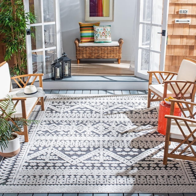 SAFAVIEH Cabana Arielle Tapis Géométrique Intérieur/extérieur en Noir et Blanc avec motifs de Losanges et Floraux, Exposé sur une Véranda Ensoleillée avec Chaises à Cadre en Bois avec Coussins Blancs, une table d'Appoint en Céramique Rouge, des Plantes en Pot et des Portes Françaises Ouvertes Menant à un Banc en Osier avec des Coussins Colorés. Ce Tapis Extérieur durable Est Idéal pour les Zones Occupées Intérieures Ou Extérieures comme les Terrasses et les patios.