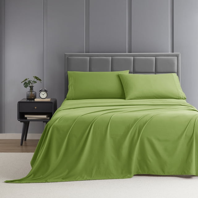 Nestl Queen Sheet Set, 1800 Series Microfiber Deep Pocket 4 Piece Bed Sheet Set displayed on a bed in a modern bedroom. The set includes a fitted sheet, flat sheet, and two pillowcases in a vibrant green color. The sheets feature a double-brushed microfiber fabric for softness, deep pockets for mattresses up to 16 inches, and a classic stripe detail. The bed is styled with a grey upholstered headboard, a black nightstand with decor, and a neutral carpeted floor.