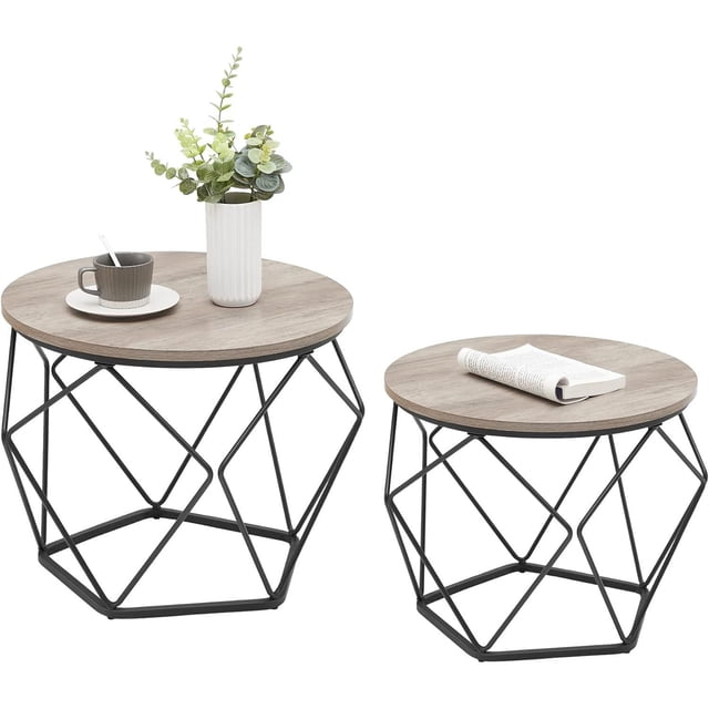 Boutique Home modern geometric design round coffee accent tables set of 2 side tables with light wood particleboard tops and black steel geometric bases, one large and one small, styled with a cup and saucer and a vase with greenery on the larger table and a rolled newspaper on the smaller, ideal for compact living spaces and versatile use.