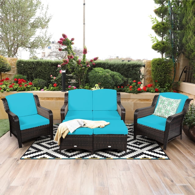 Costway 5PCS Patio Rattan Furniture Set featuring a loveseat, two single sofas, and two ottomans with turquoise cushions. The set is made of durable PE rattan in a mix brown finish and includes thick, high-resilience cushions for comfort. The ottomans can double as coffee tables when the cushions are removed. Shown in an outdoor patio setting with a patterned rug and vibrant garden backdrop.