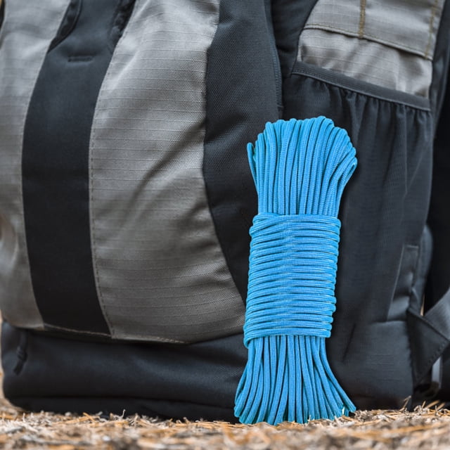 Pisexur Outdoor Nylon 9-core Umbrella Rope Camping Emergency Paratrooper Wind Rope Tent Canopy Rope in a vibrant blue color, coiled neatly and placed against a black and grey backpack on a natural outdoor surface. The rope measures 15 meters in length, has a diameter of 0.4 cm, and features high-strength 9-core construction with a tensile strength of 320. Ideal for camping, emergency kits, and crafting items like bracelets or lanyards.