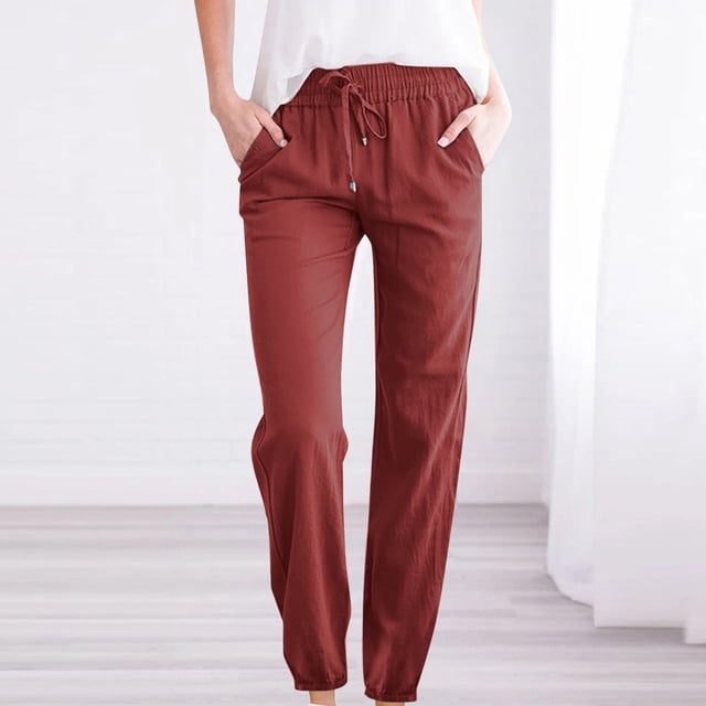 RKSTN Womens Pants Woman Solid Color Cotton And Linen Drawstring Elastic Waist Long Straight Pants. These lightweight, soft, and breathable pants feature a solid color design, elastic waistband with drawstring, and straight-leg fit. Made from cotton and linen, they include convenient side pockets and are suitable for casual, work, or vacation wear. Shown in a reddish-brown color, styled with a white top in a bright indoor setting.