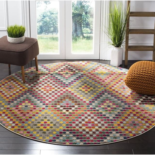 Safavieh Monaco Linton Geometric Area Rug, round with vibrant multicolored geometric dot and diamond patterns in durable polypropylene with mixed loop pile, on dark hardwood floors in a bright room featuring a brown stool with a green plant, an orange knitted pouf, and a white vase with tall grass near glass doors, suitable for adding Bohemian flair to living spaces.