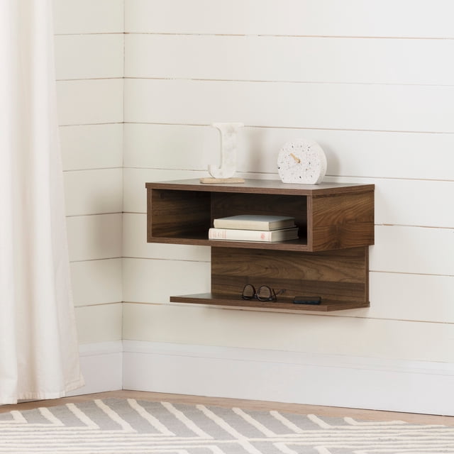 South Shore Sazena Floating Nightstand for Adult in natural walnut, wall-mounted bedroom furniture with an open upper shelf holding books and a lower shelf with glasses and a phone, designed for versatile storage and modern space-saving, set against white shiplap walls with a light curtain and patterned rug.