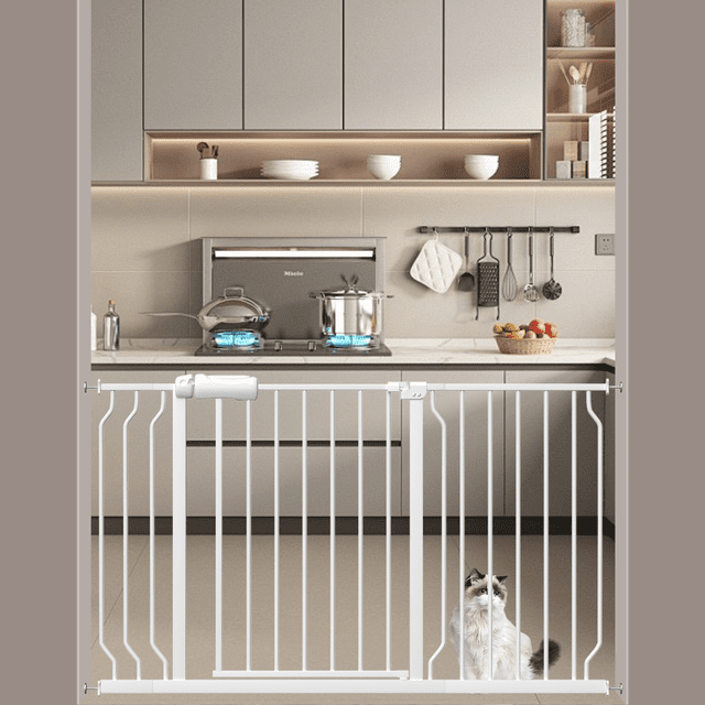 48-57" Extra Wide Pet Gate for Doorway, Pressure-Mounted Dog Gate shown installed in a modern kitchen doorway. The white metal gate features vertical bars, a walk-thru design with a one-handed latch, and a pressure-mounted setup for easy installation without wall damage. Suitable for children aged 6–24 months and small to medium pets, the gate adjusts to fit openings from 48 to 57 inches wide and stands 30 inches tall. A cat is visible behind the gate, demonstrating its use for pet containment.