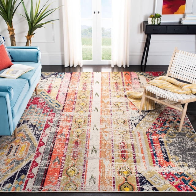 Safavieh Madison Christabella Overdyed Striped Area Rug with multicolored distressed vertical stripes in red, orange, yellow, cream, and navy blue, placed in a living room featuring a light blue sofa, woven chair with a yellow throw, and potted plants near white French doors, suitable as a transitional accent rug.