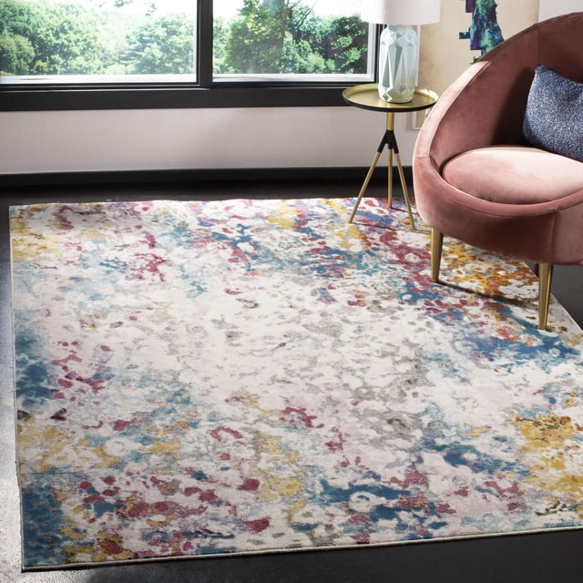 Safavieh Aria Augustin Abstract Area Rug with a distressed abstract pattern in vibrant blue, yellow, red, and gray on a light background, made of durable synthetic yarns for high-traffic areas, displayed in a modern room with a pink velvet chair and gold tripod side table by a window, also suitable as a decorative accent for contemporary interiors.
