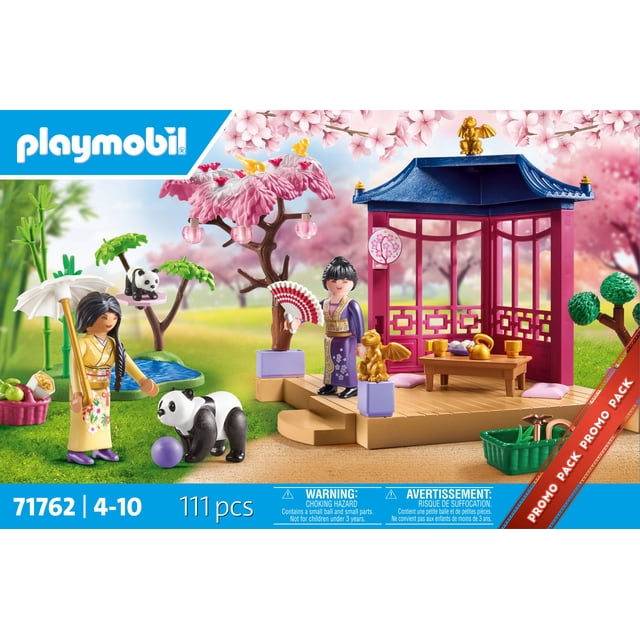 Playmobil Asian Garden with Panda Play Set featuring a pink and blue pavilion with golden dragon statues, a tea table with cups and teapot, two figures in traditional Asian attire, playful pandas near a purple ball, cherry blossom trees with hanging lanterns, bamboo plants, and garden accessories including a basket of apples and gardening tools on green grass.
