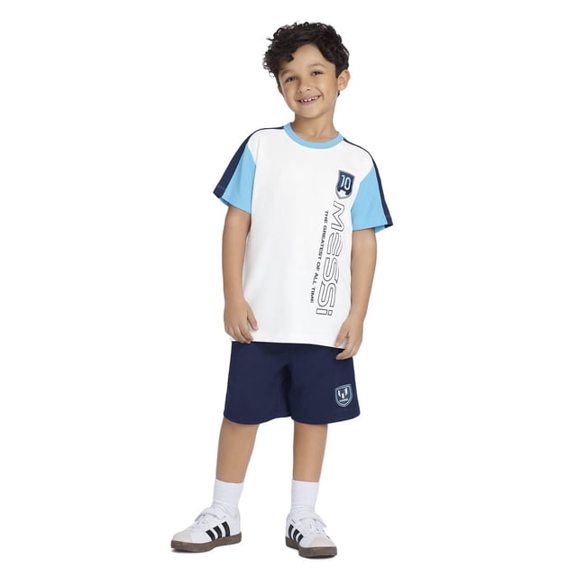 Messi t-shirt pour Enfants Mettant en Vedette un t-shirt Blanc pour Garçons avec Manches Bleu Pâle et Rayures aux Épaules Bleu Marine, logo Messi vertical et Texte « le Plus Grand de Tous les Temps » à l'Avant, Assorti à des shorts Bleu Marine avec un Emblème Messi, Lavable à la machine et Convient au Port Quotidien.